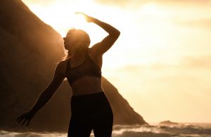 woman doing yoga on beach at sunset